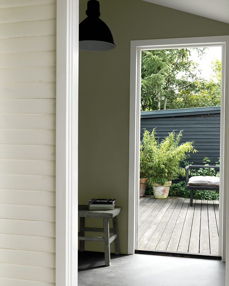 De grønne veggene og trebenken skaper harmoni mellom boligen og naturen